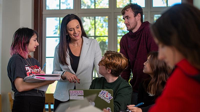 Staff person casually talking with small group of students